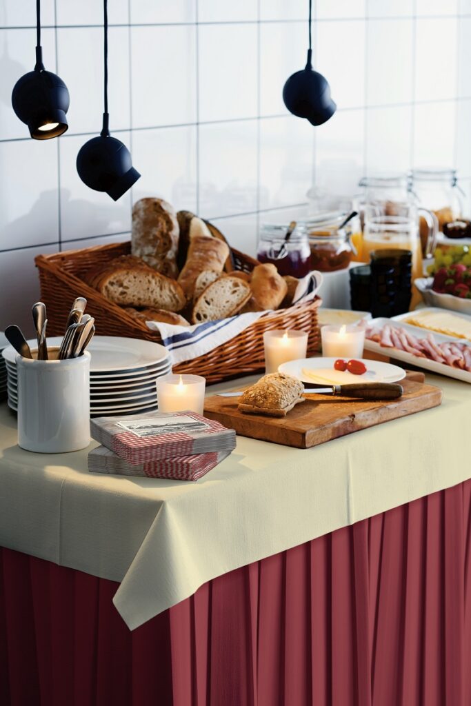 Frühstücksbuffet mit weinrotem Tischvorhang und beiger Tischdeckenrolle von Duni.