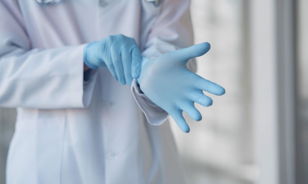 Ein Laborant zieht hellblaue Einmalhandschuhe an.