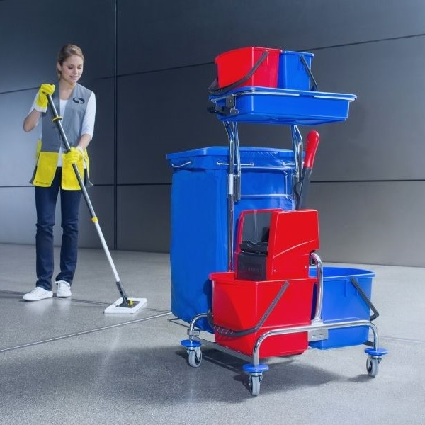 Modularer rot-blauer Reinigungswagen mit Wischmoppsystem. Im Hintergrund eine Raumpflegerin mit Wischmopp.