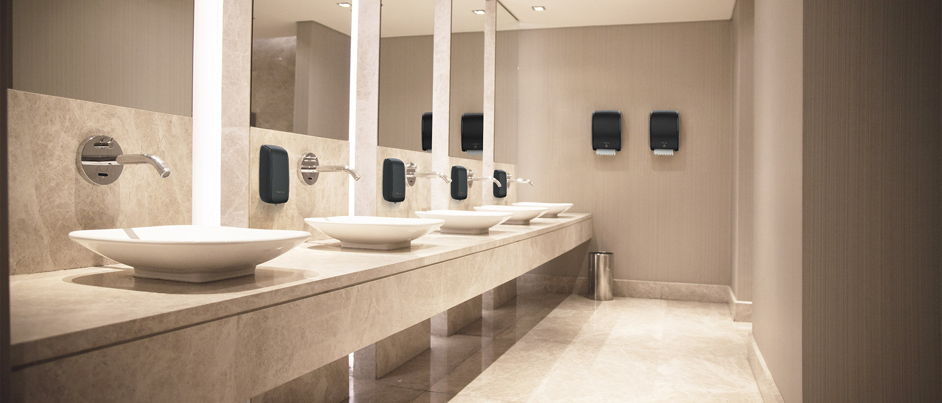 Toiletten-Vorraum mit eleganten Waschbecken und 2 schwarzen Tubeless-Papierhandtuch-Spendern.